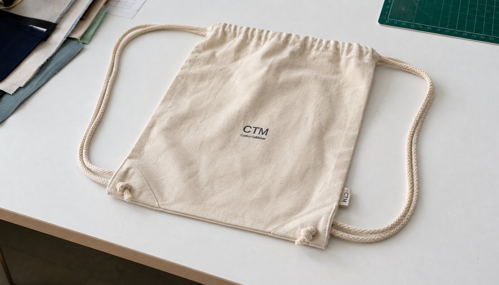Natural cotton drawstring backpack with a sample logo printed on the front in a clean factory sample room