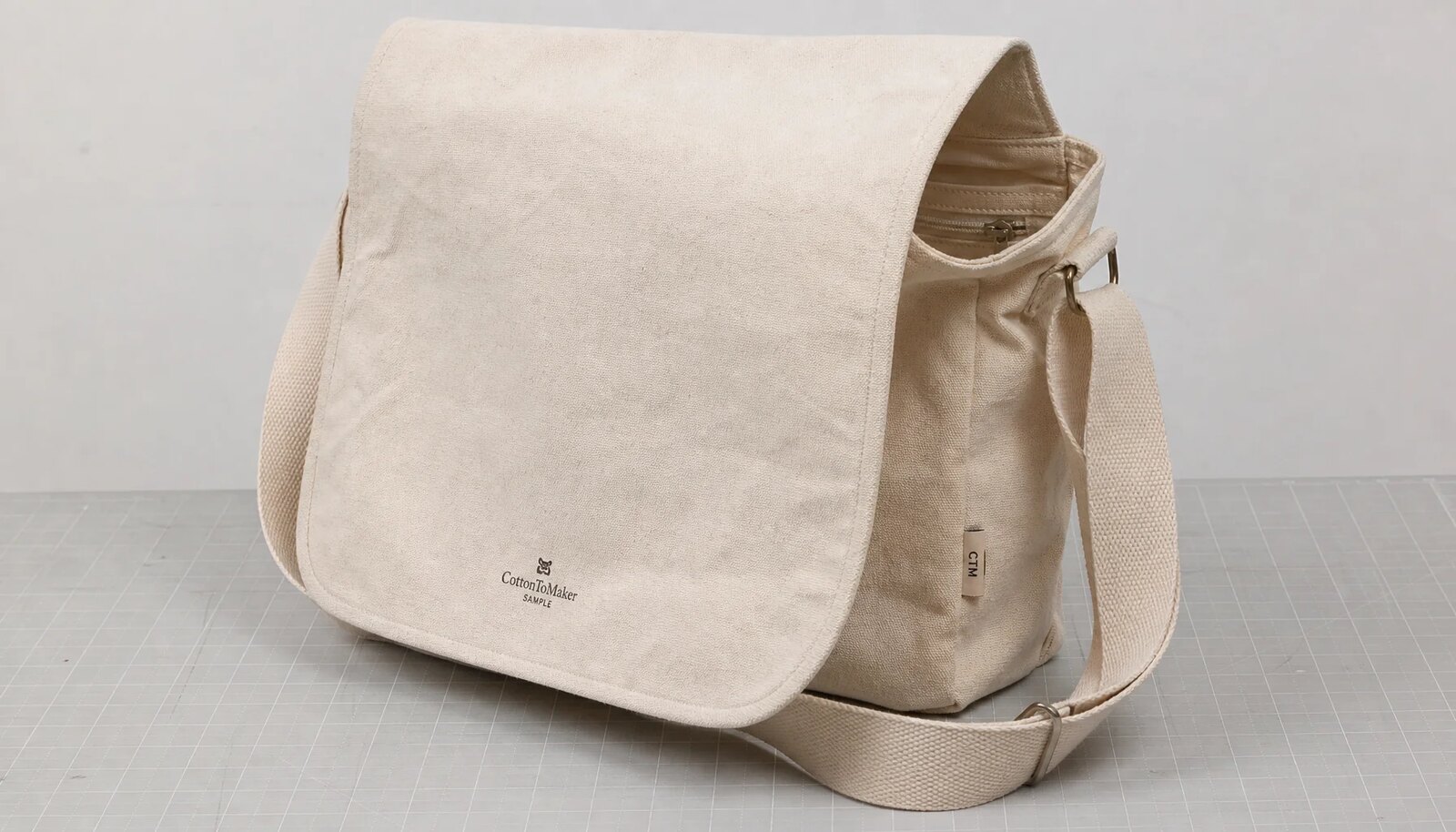Natural canvas messenger bag with CTM woven side label and CottonToMaker sample logo for hotel retail quality inspection