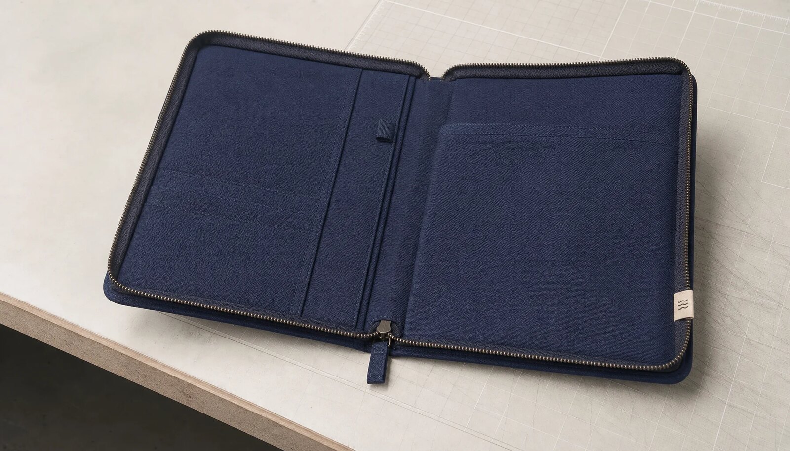 Navy canvas zipper portfolio with CTM CottonToMaker side label and visible zipper construction in a factory sample room