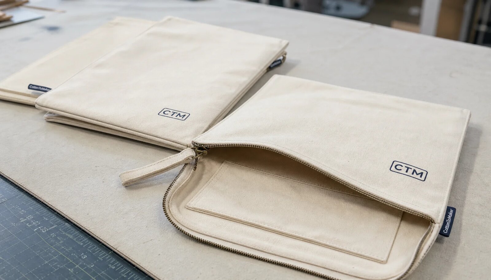 Natural canvas zipper portfolios with CTM logo and woven CottonToMaker side label in a sample room