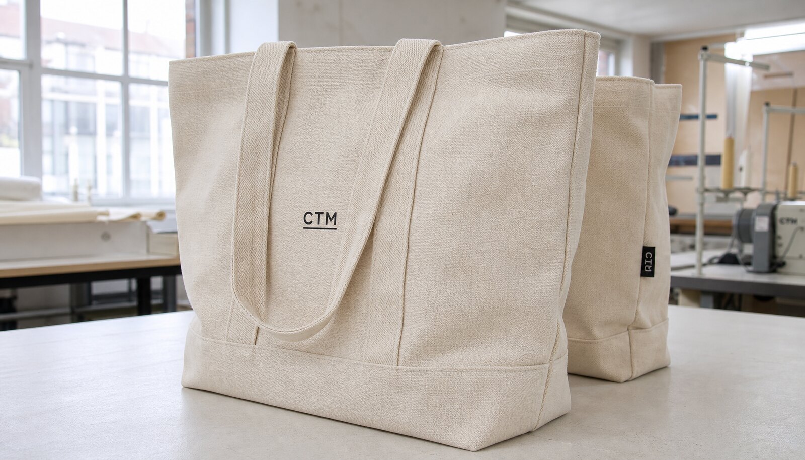 Cotton canvas tote bag with a simple CTM logo printed directly on the front in a factory sample room