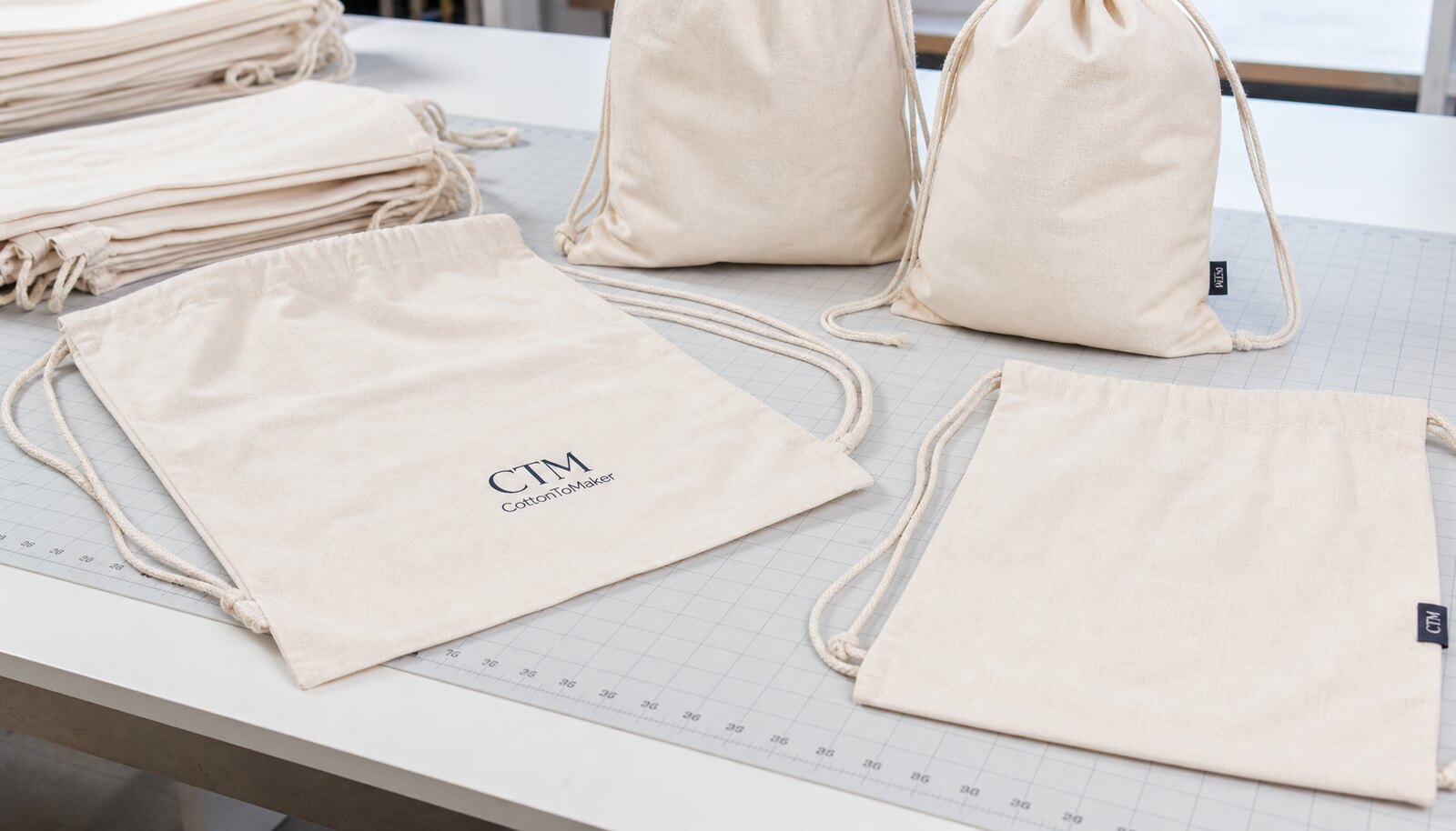 Cotton drawstring backpacks with a simple CTM logo shown in a factory sample room