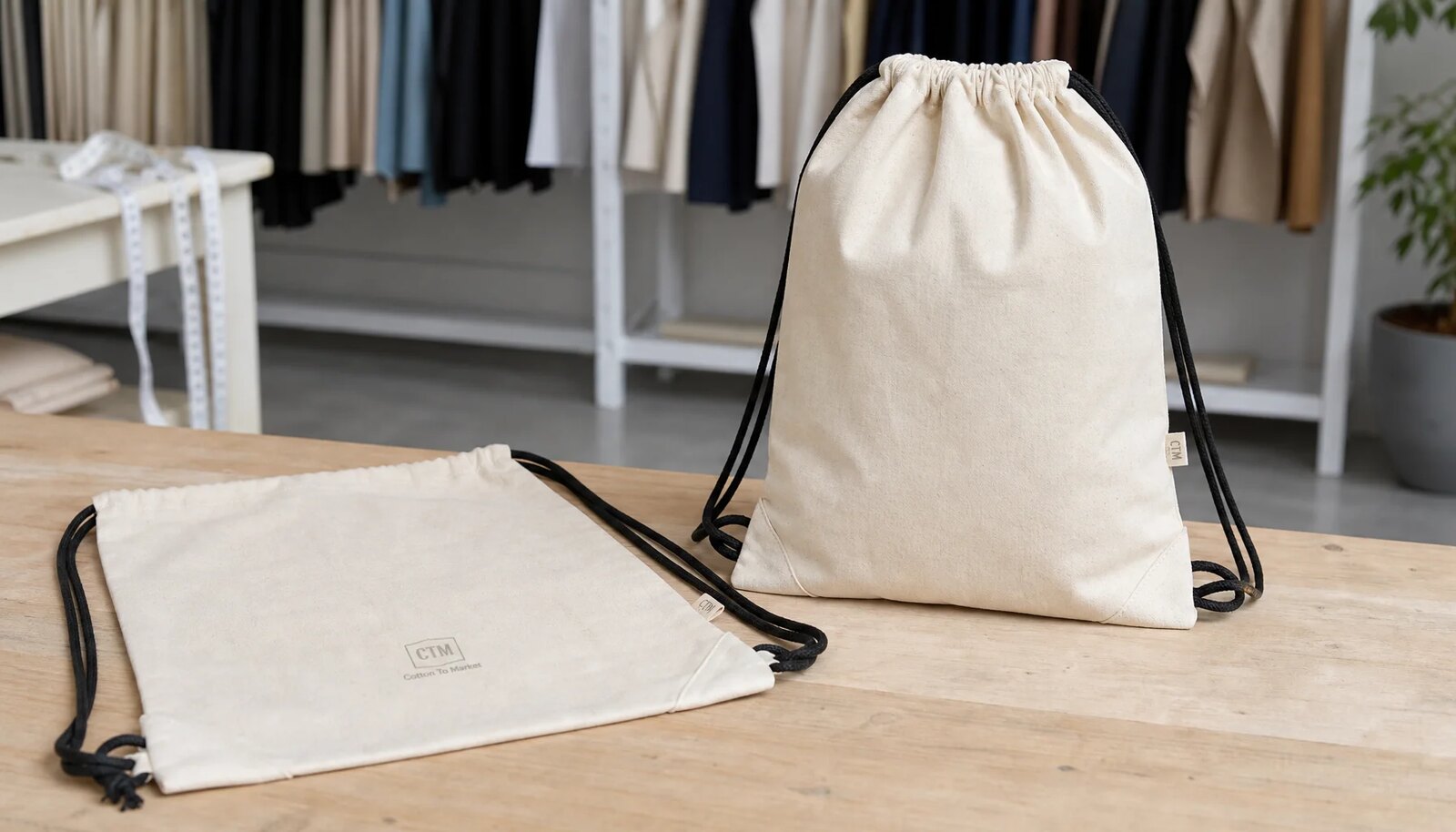 Natural cotton drawstring backpack sample with CTM CottonToMaker logo on a factory sample table