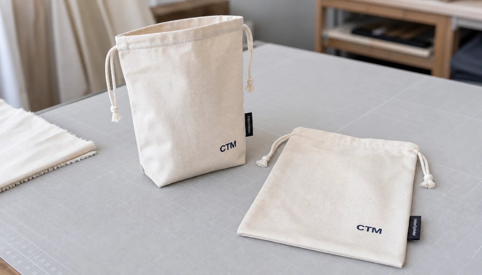 Natural cotton drawstring pouches with CTM logo and woven CottonToMaker side label for university bookstore sourcing