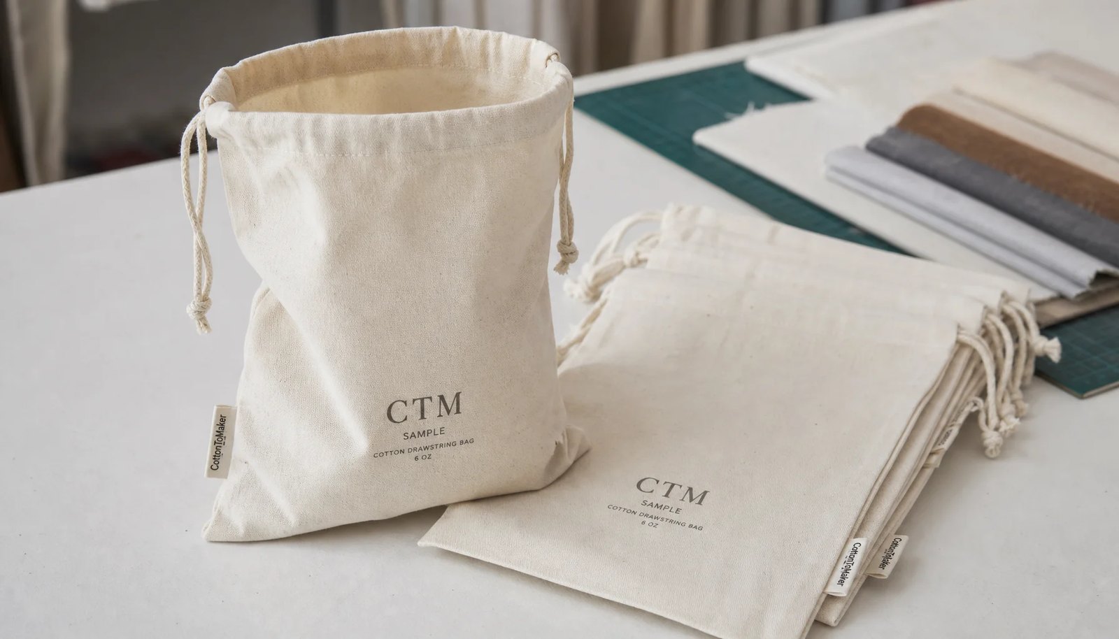Natural cotton drawstring pouches with CTM printed sample logo in a factory sample room