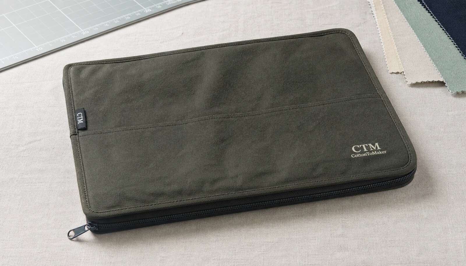 Custom canvas zipper portfolio with CTM sample logo shown in a clean factory sample room