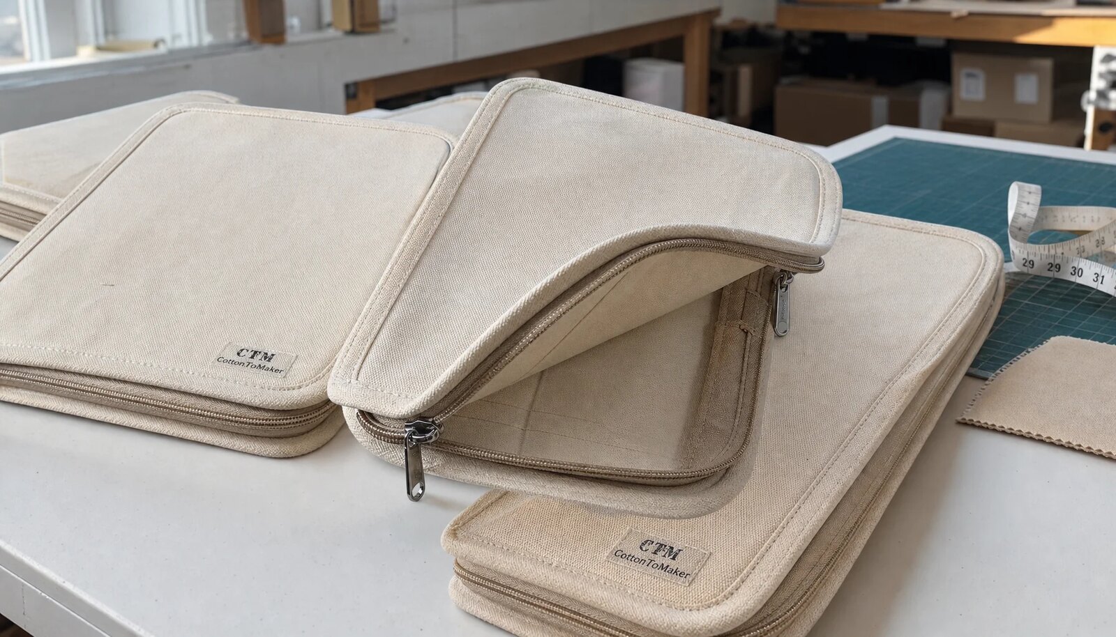 Custom canvas zipper portfolios with a simple CTM logo shown in a factory sample room
