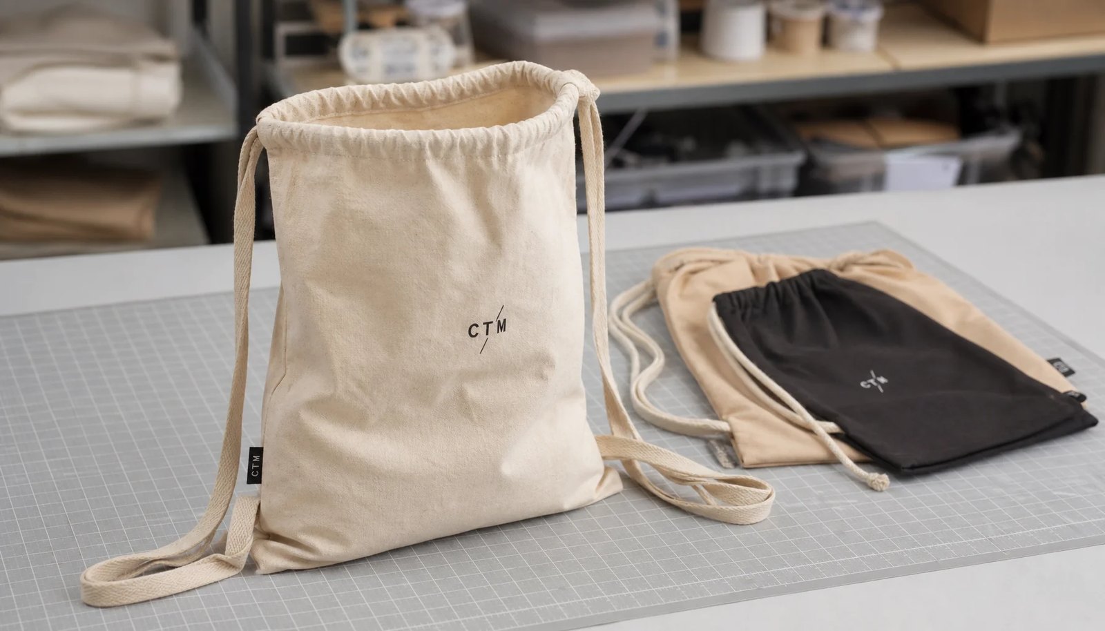 Custom cotton drawstring backpack sample with CTM logo showing fabric texture, rope drawcord, and side label