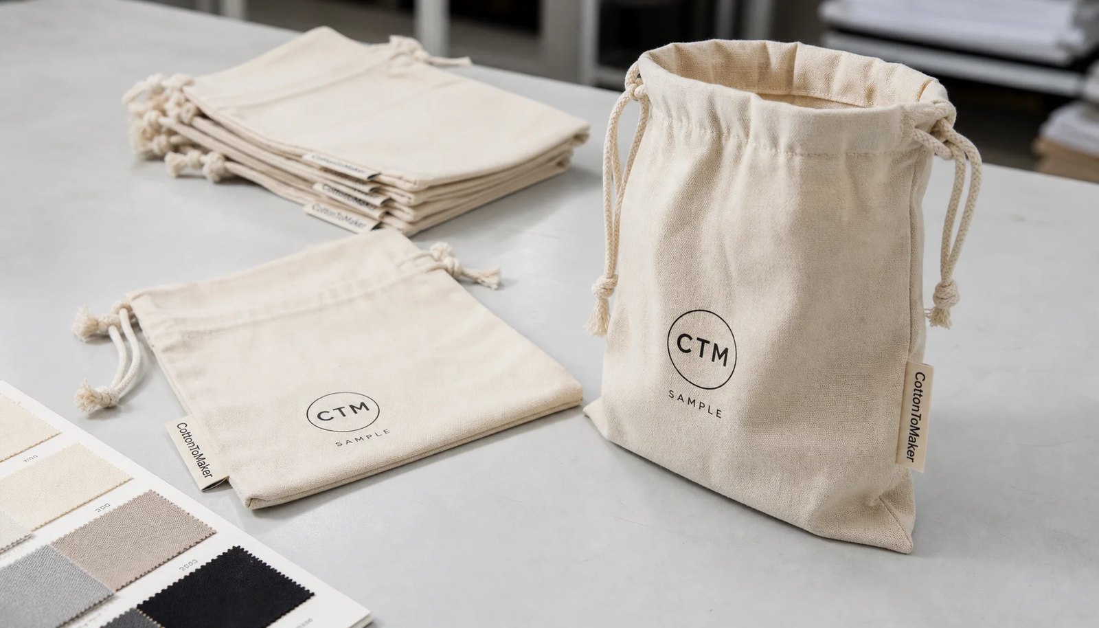 Natural custom cotton drawstring pouches with CTM logo print and CottonToMaker side label in a sample room