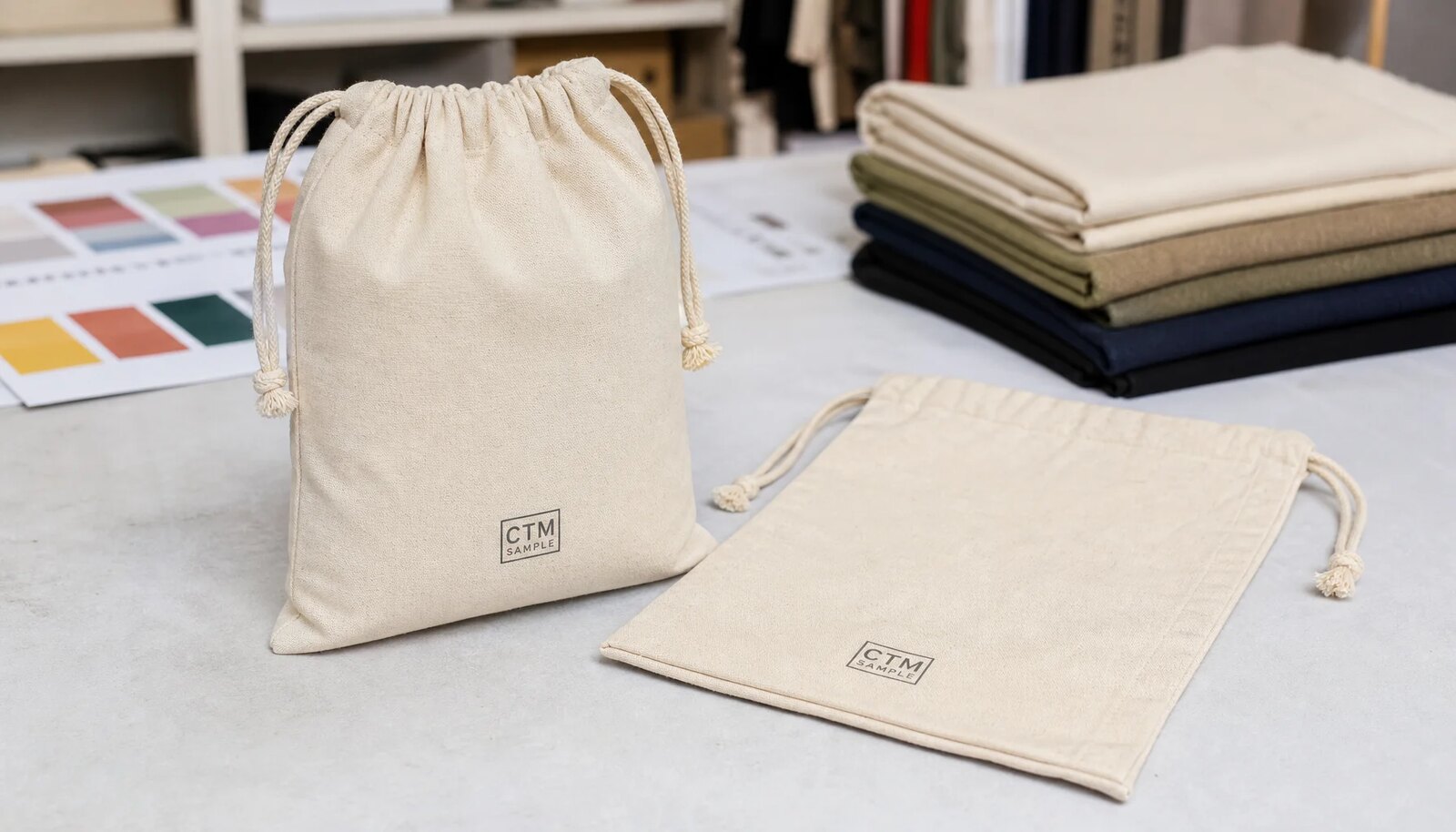 Custom cotton drawstring pouches with CTM logo printed on the front panel in a clean sample room