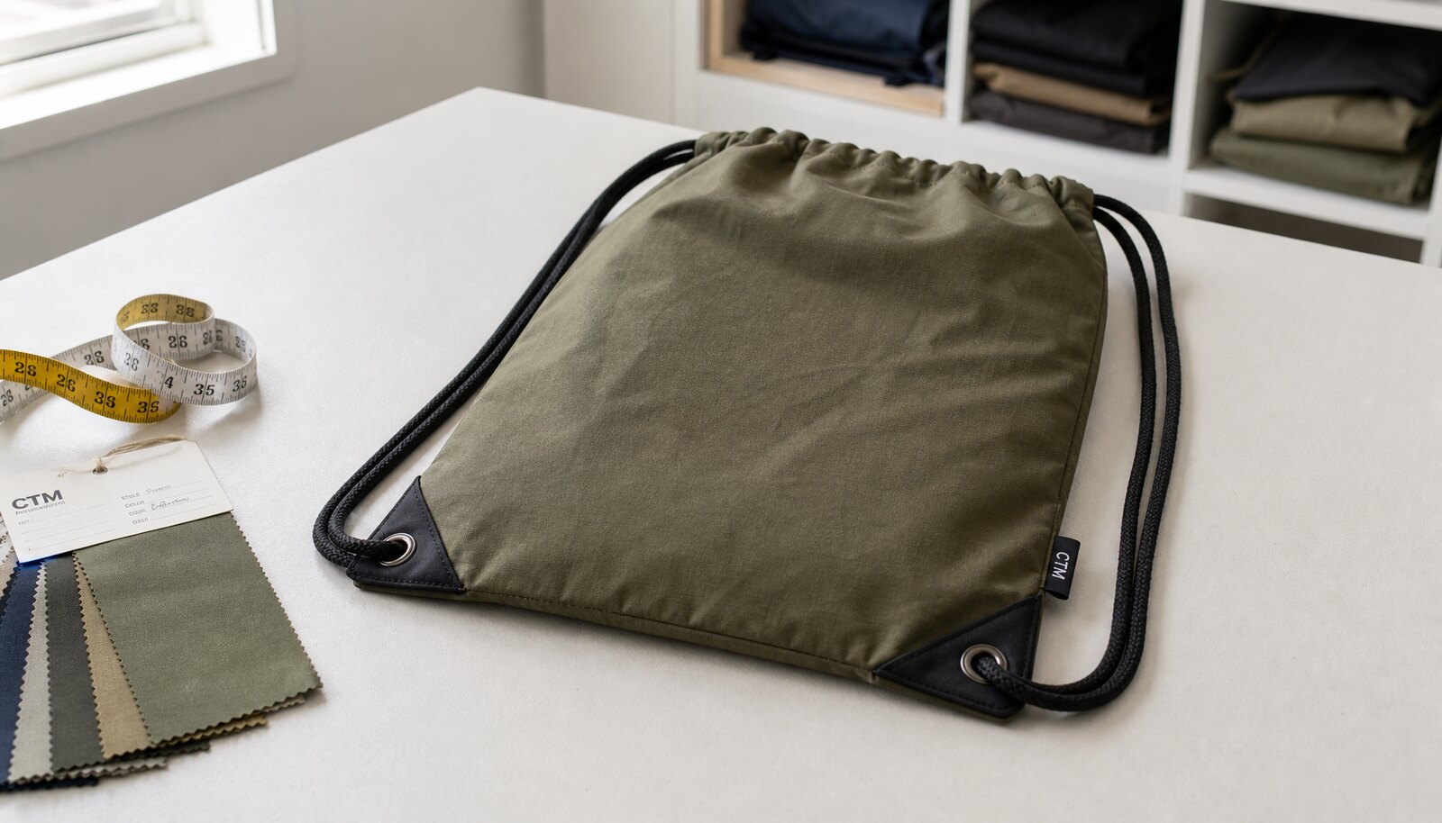 Photorealistic custom drawstring backpack sample with a simple CTM logo in a factory sample room