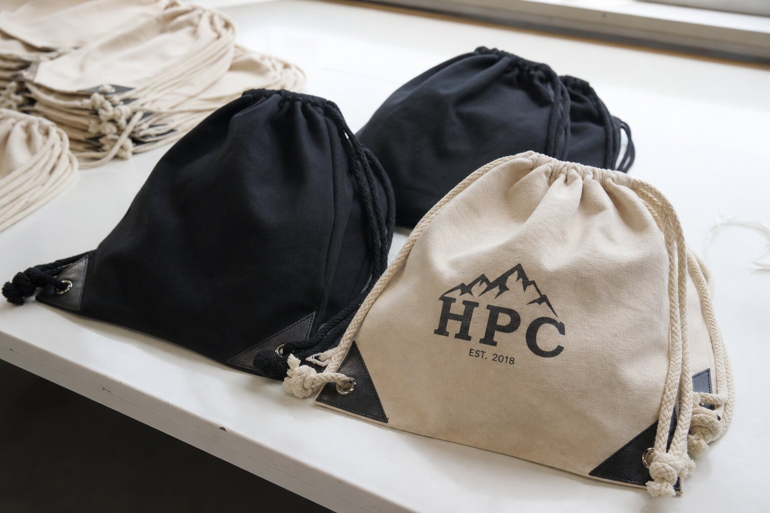 Custom drawstring backpacks with printed logo and reinforced corners on a factory inspection table