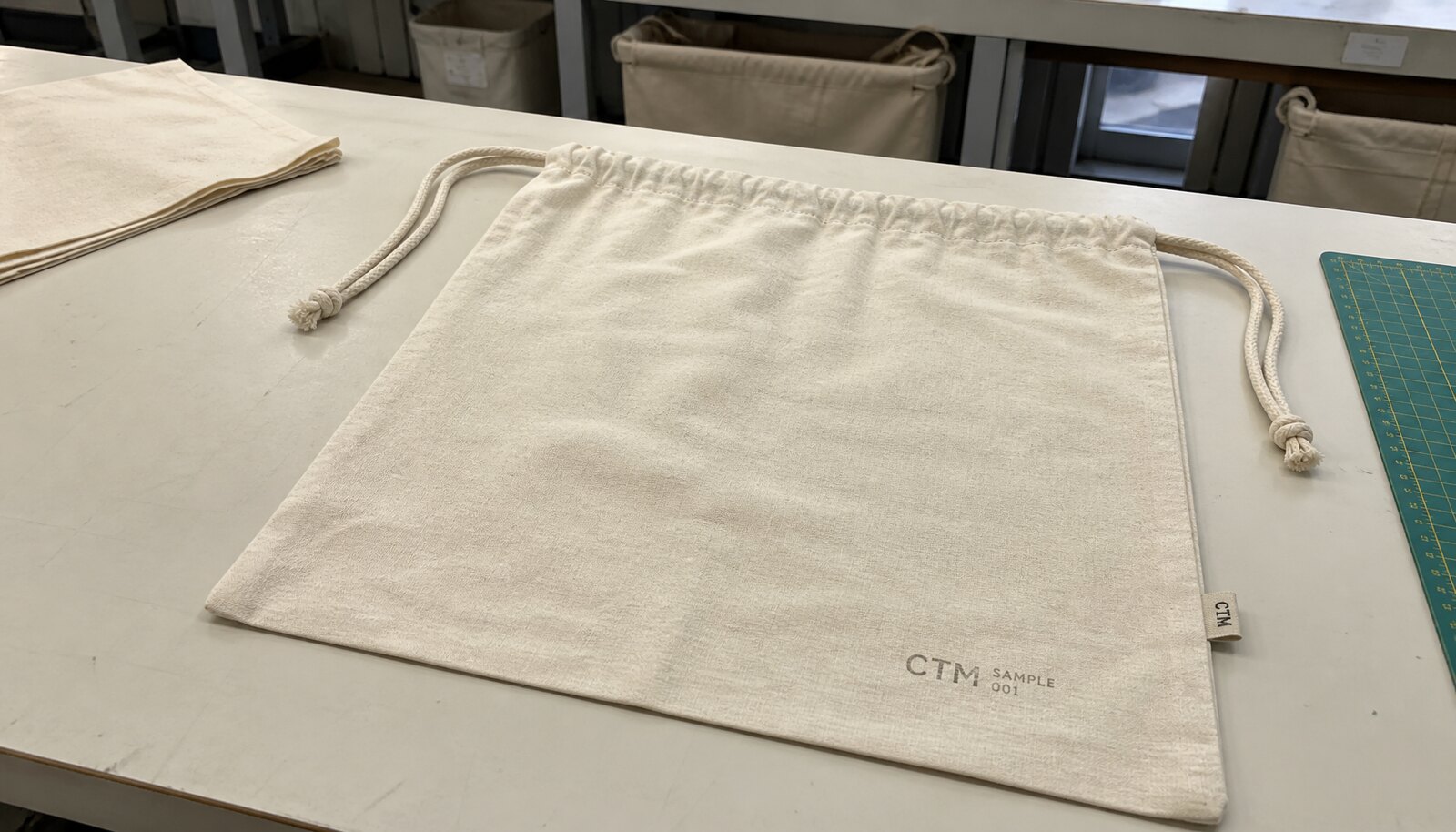 Photorealistic custom drawstring bag with a simple CTM sample logo printed on the bag in a factory sample room
