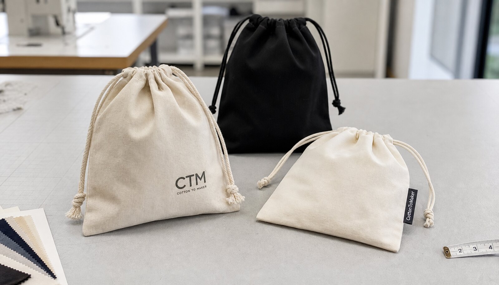 Custom drawstring pouches with a simple CTM logo shown in a factory sample room