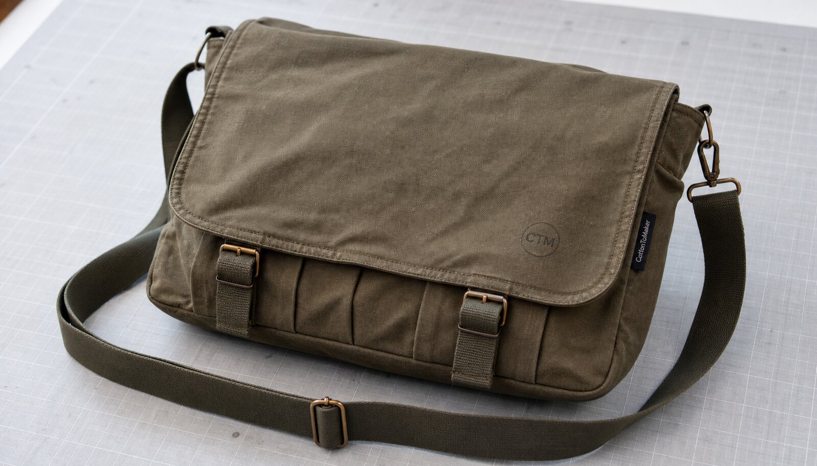 Canvas messenger bag with a simple CTM sample logo shown in a clean factory sample room