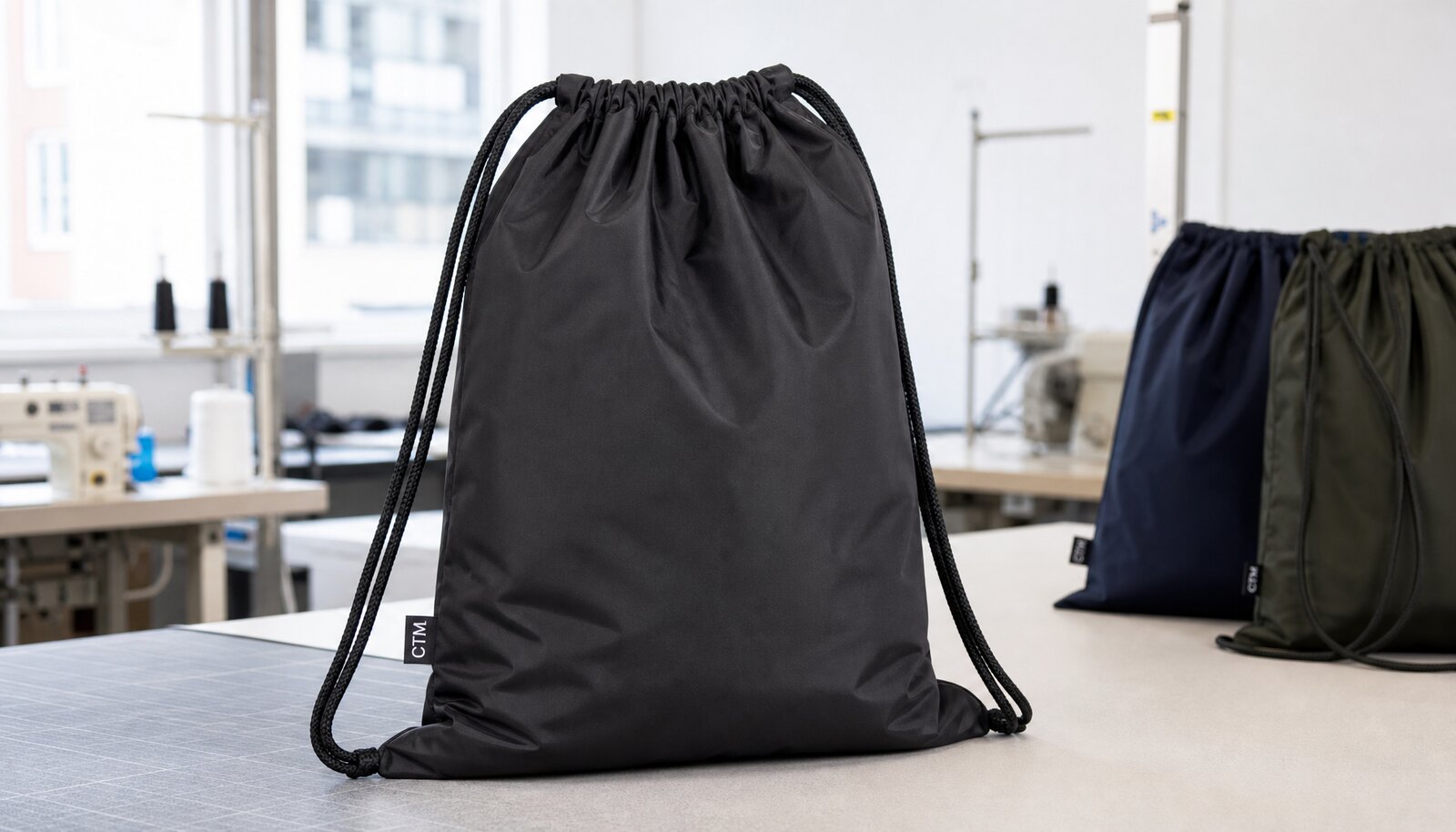 Custom nylon drawstring bag with a simple CTM logo printed on the front in a factory sample room