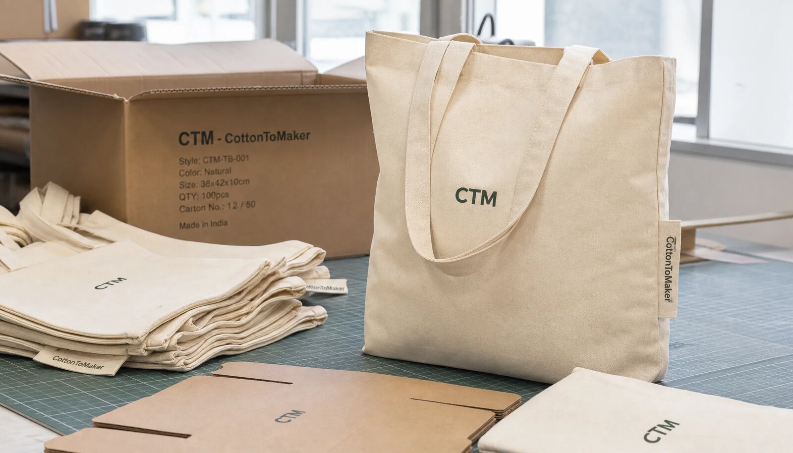 Custom organic cotton tote bags with CTM sample logo packed beside an export carton for craft fair orders