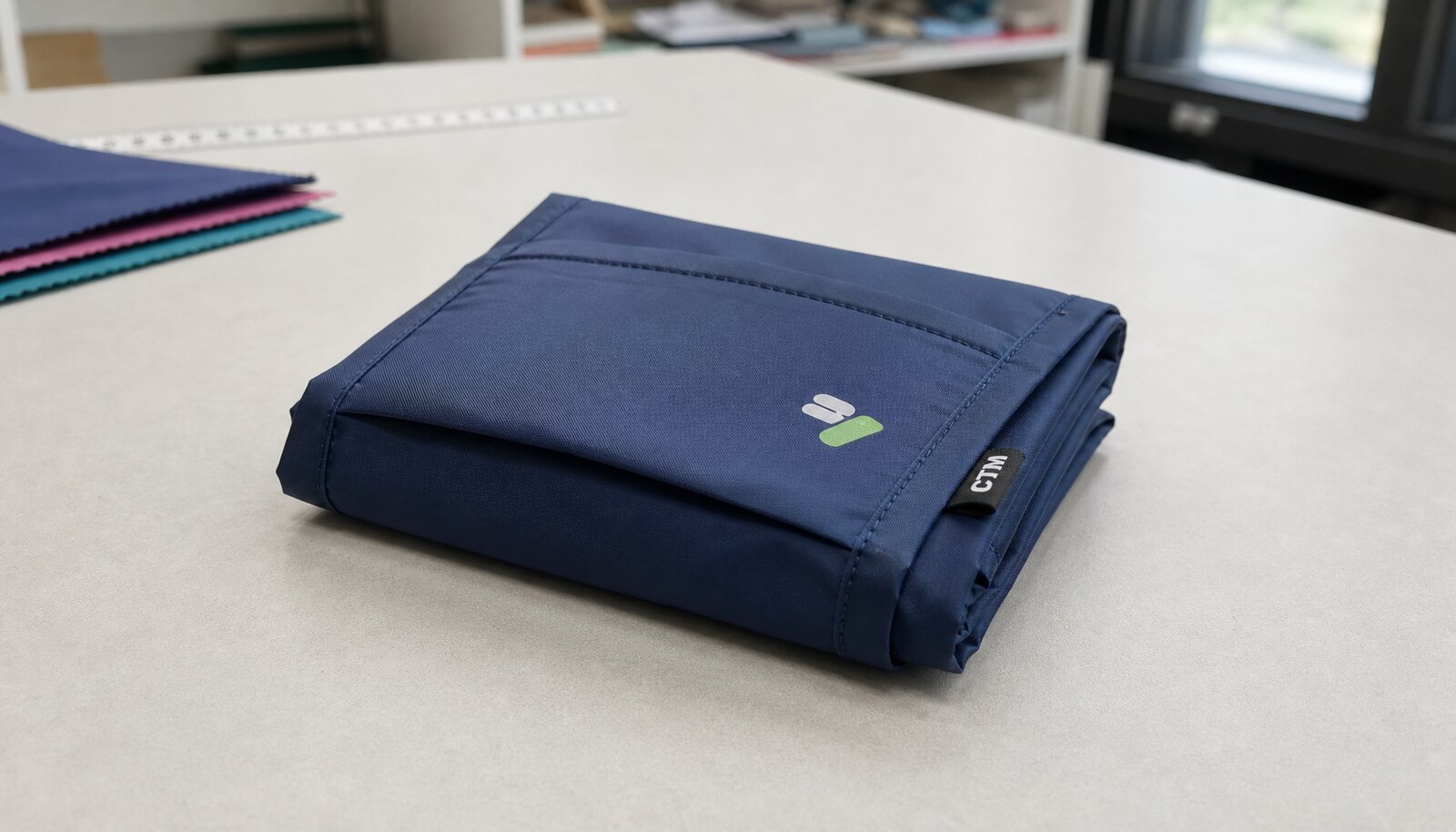 Folded reusable shopping bag with a CTM woven side label on a sample table