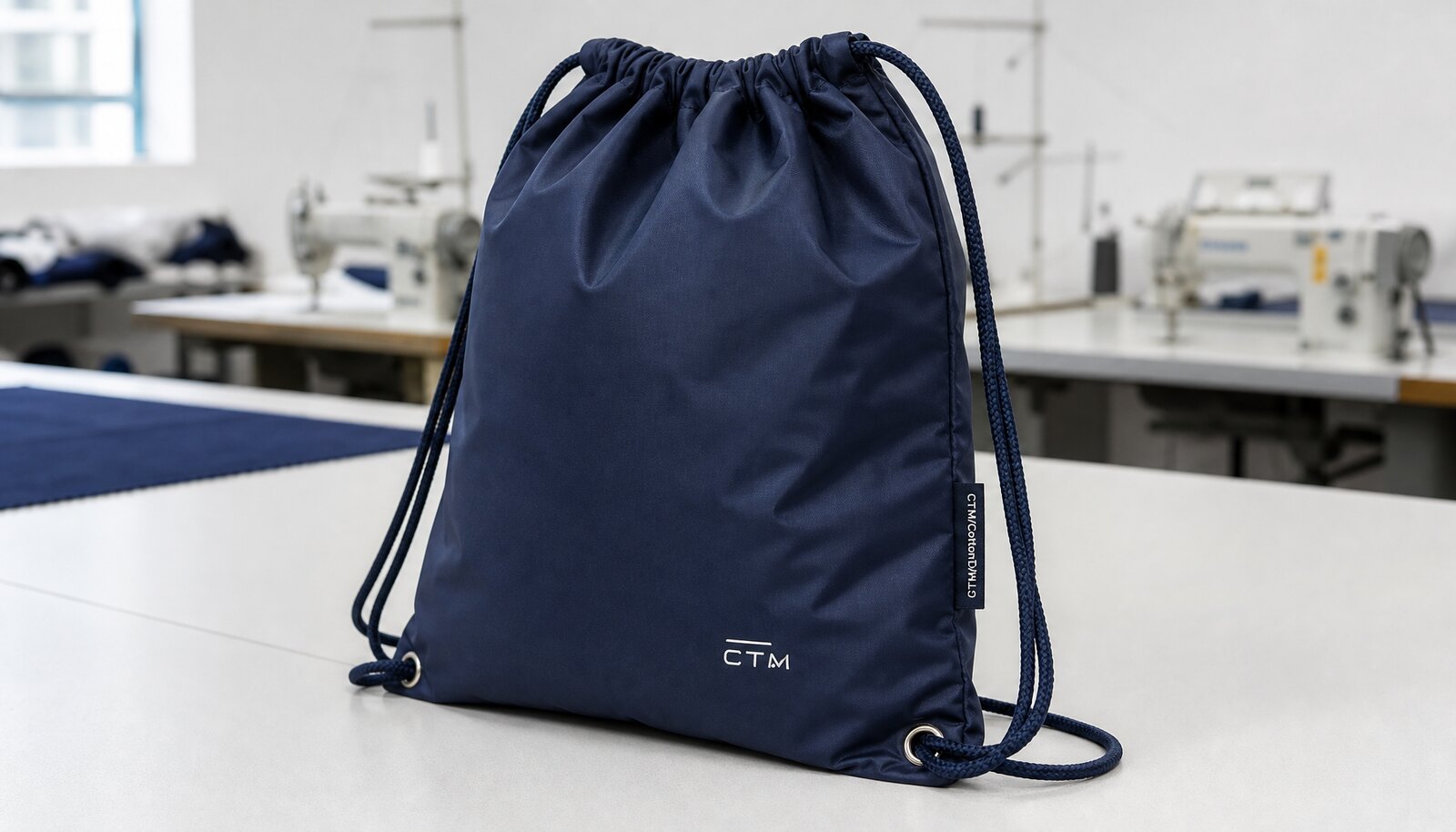 Photorealistic gym drawstring backpack with a small CTM side label and logo print in a clean sample room.