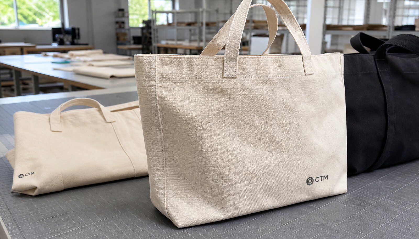 Heavy canvas tote bag with a simple CTM logo shown in a factory sample room for retail buyer review