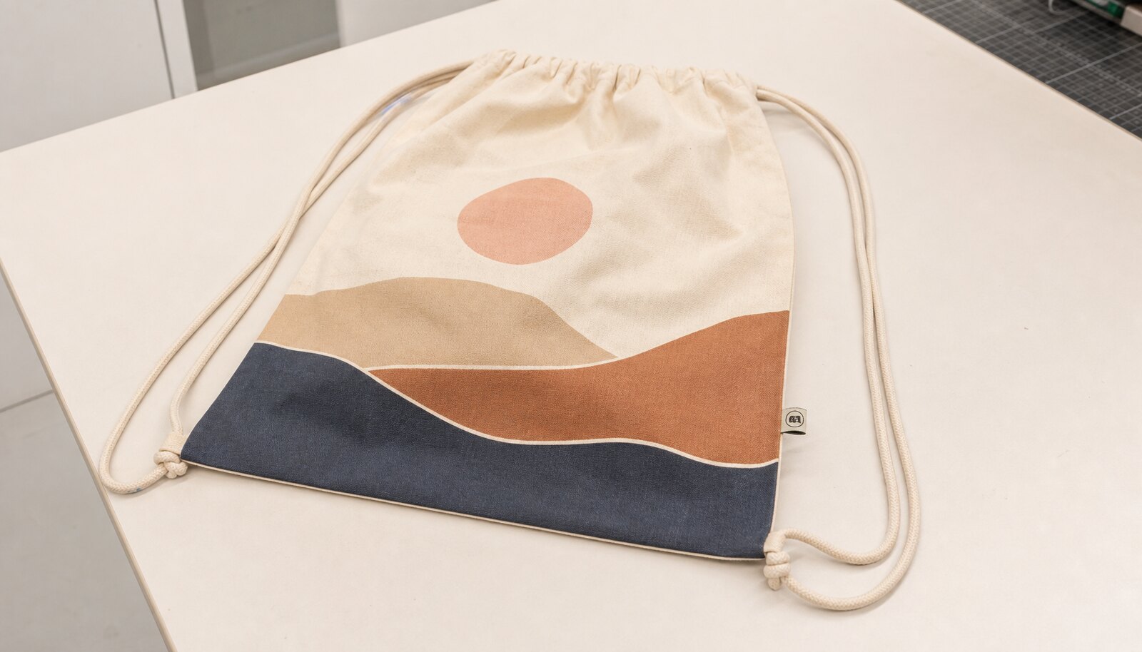 Photorealistic drawstring backpack sample with a simple CTM/CottonToMaker logo printed on the product in a clean studio setting