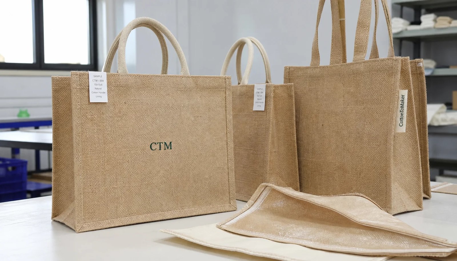 Natural jute tote bag samples with CTM logo in a factory sample room
