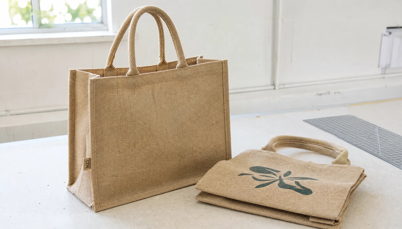 Natural jute tote bag with a CTM sample label in a factory sample room.