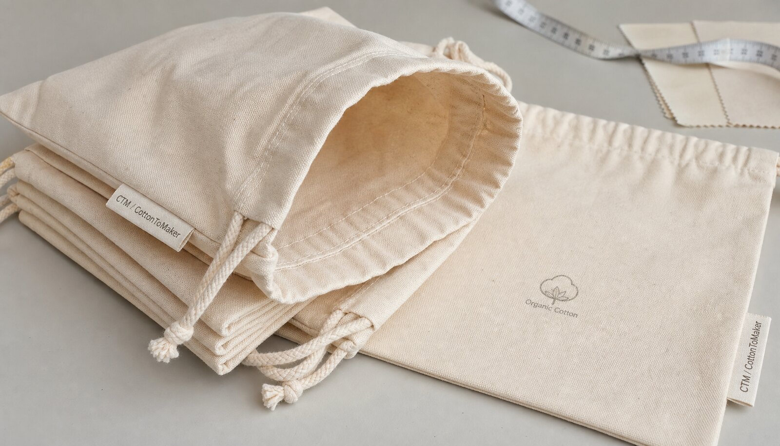 Natural organic cotton gift bags in a factory sample room with a simple CTM CottonToMaker logo printed on the bag