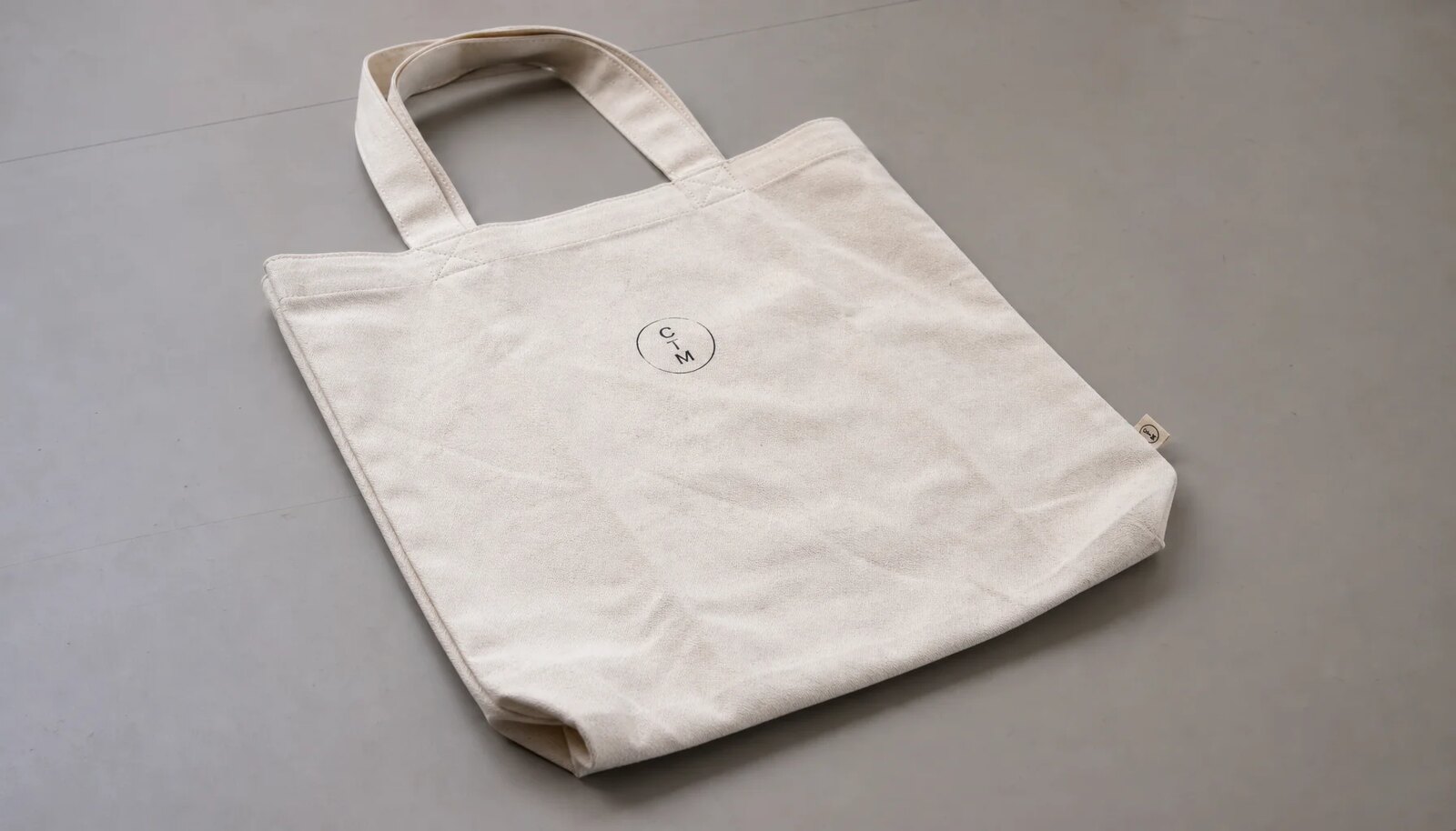 Organic cotton tote bag with a simple CTM sample logo printed in a factory sample room