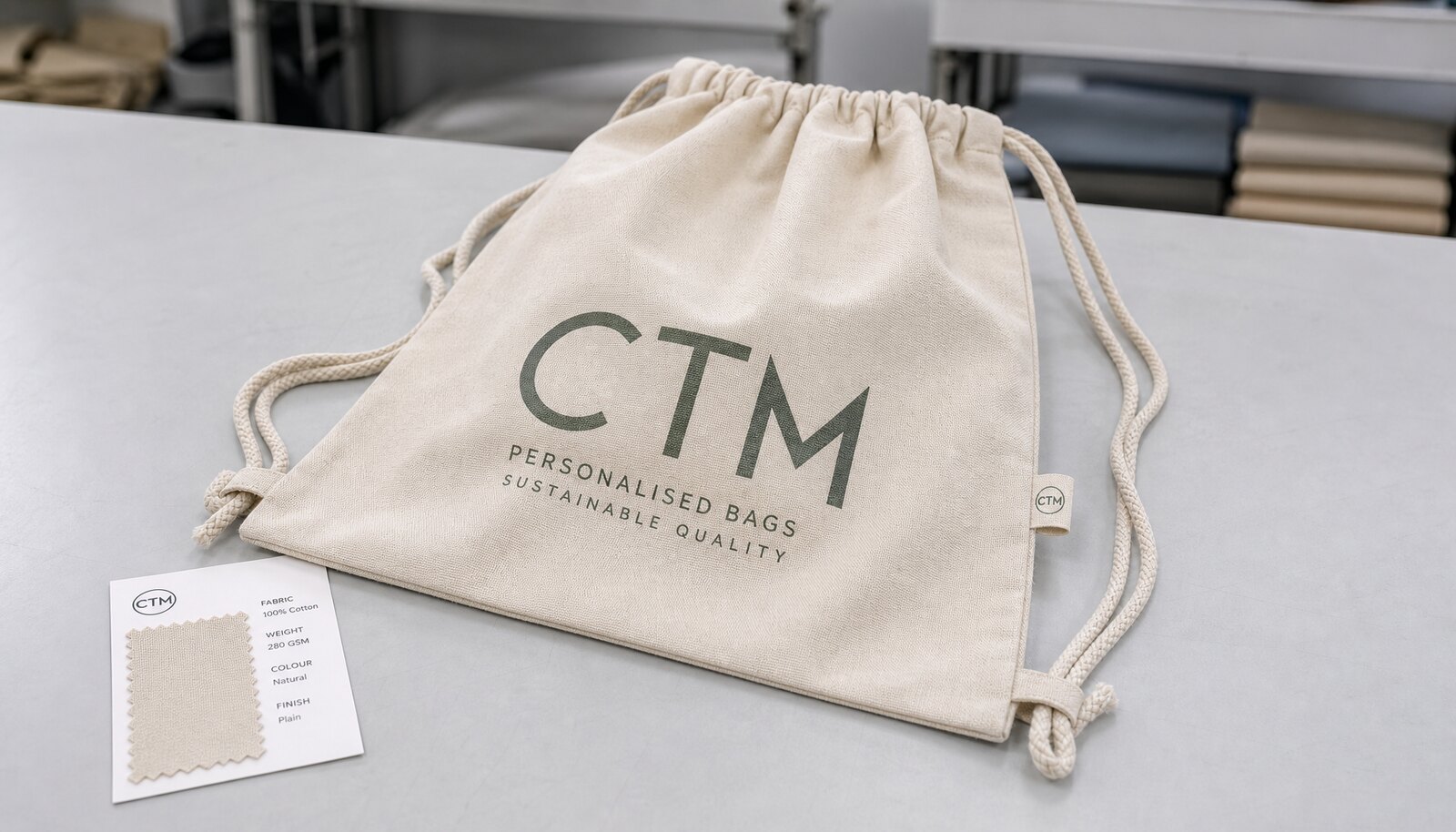 A personalised drawstring backpack sample with a simple CTM CottonToMaker side label in a clean factory sample room