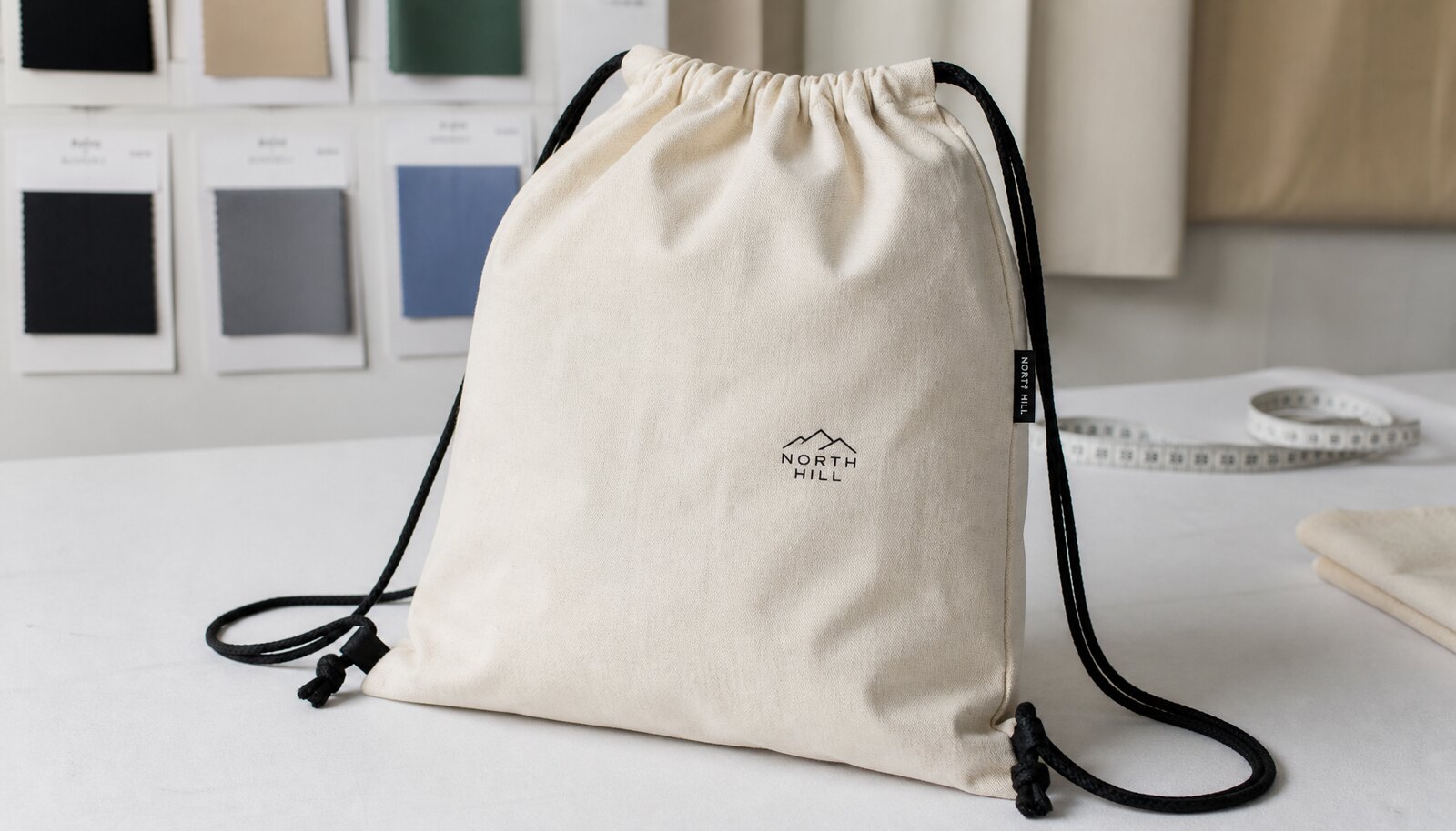 Photorealistic cotton drawstring backpack with a CTM sample logo on a clean factory worktable.