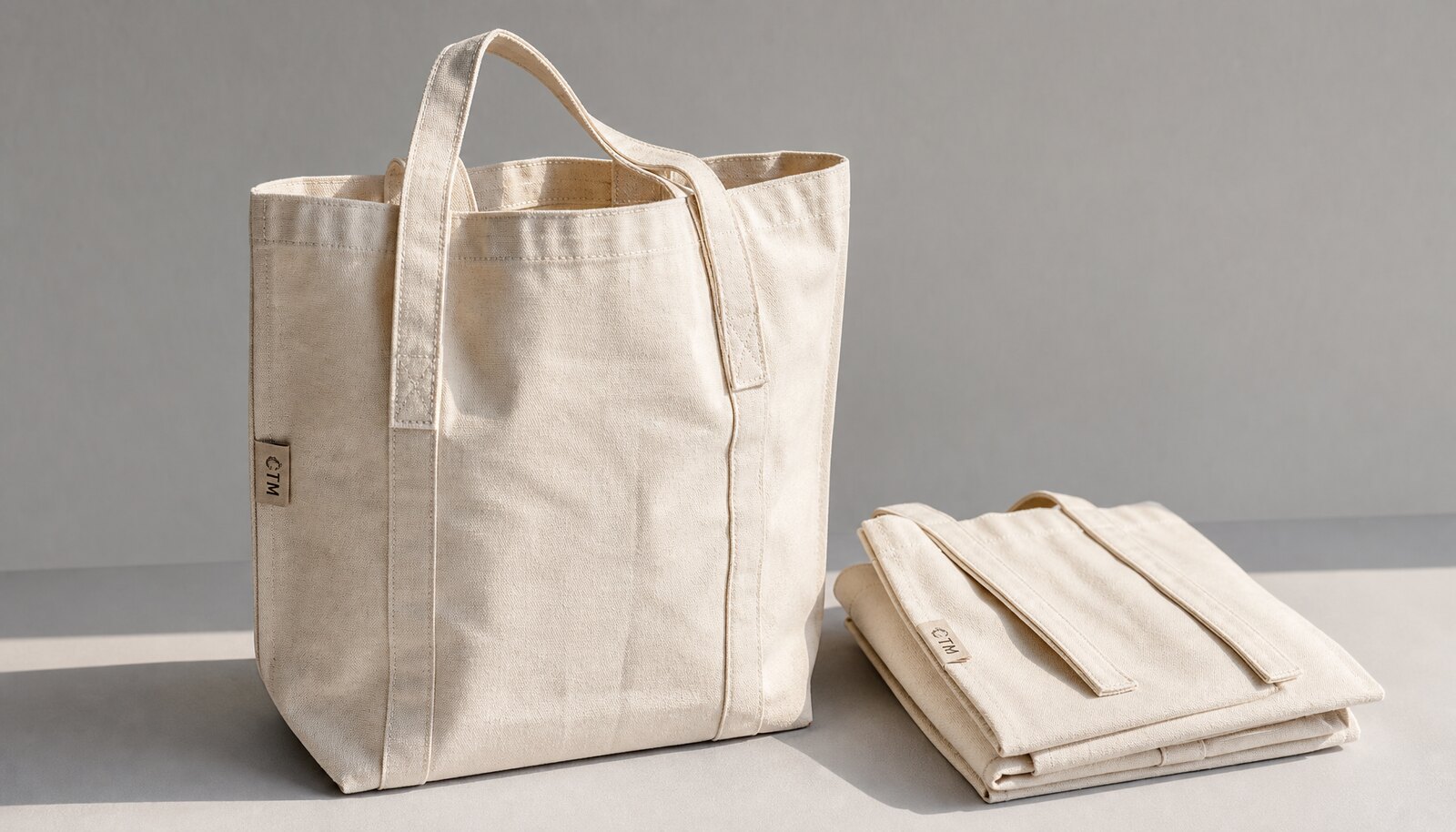 Photorealistic cotton reusable shopping bag for hotels with a small CTM CottonToMaker woven side label in a clean studio setting.