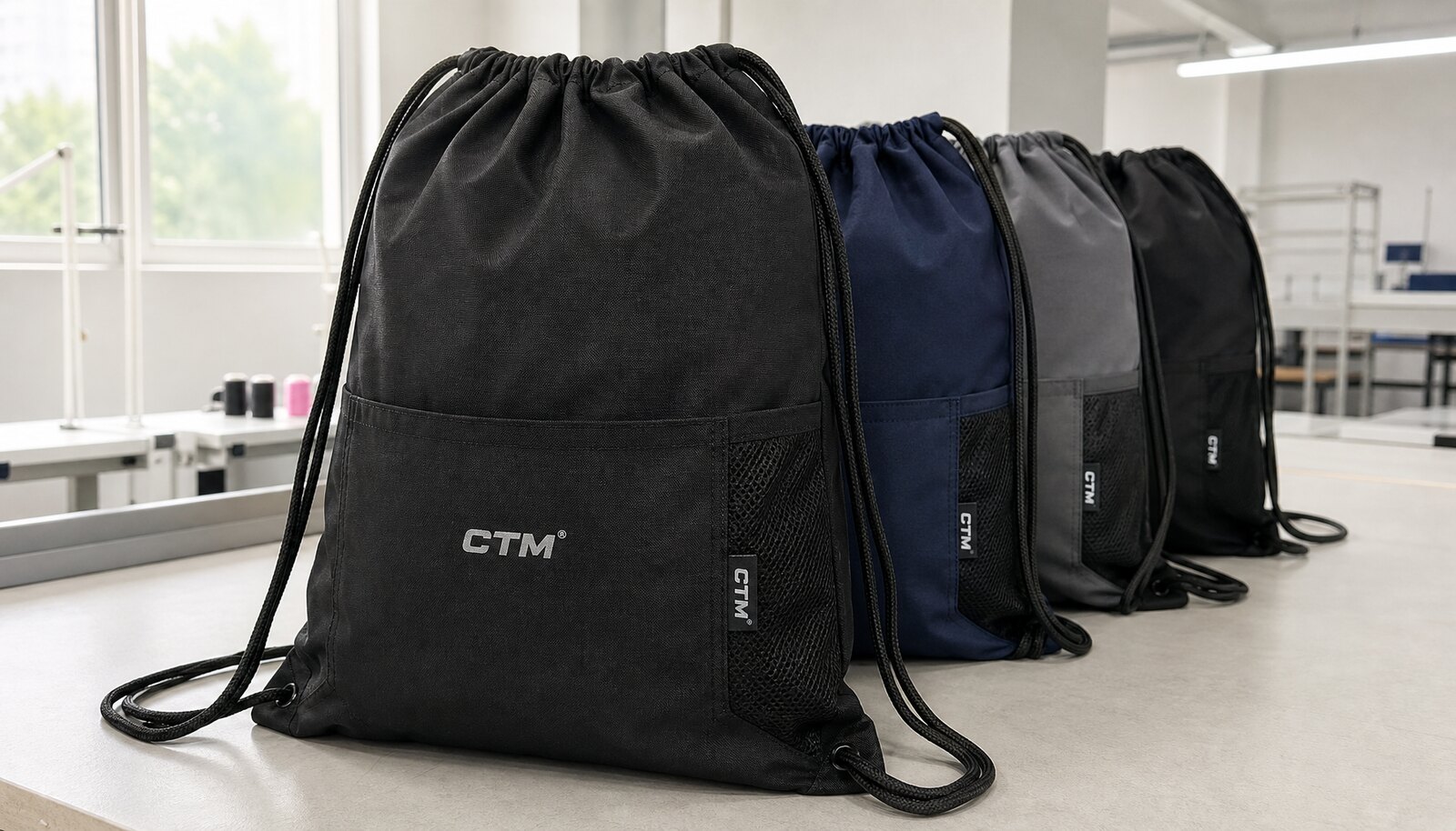 School drawstring backpacks with a simple CTM sample logo printed on the front in a factory sample room