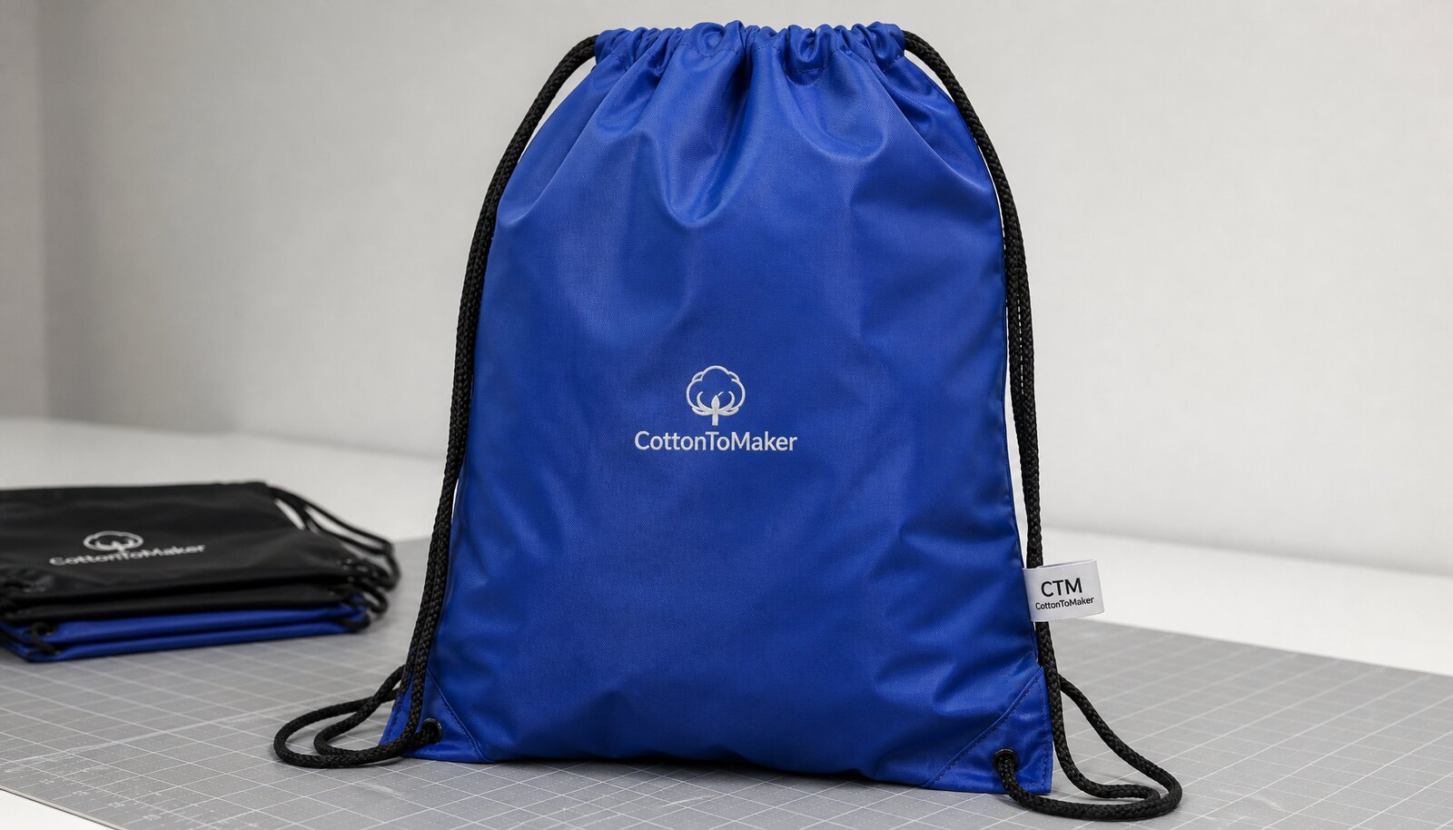 Photorealistic blue sports drawstring bag with a CTM CottonToMaker woven side label and a simple logo print