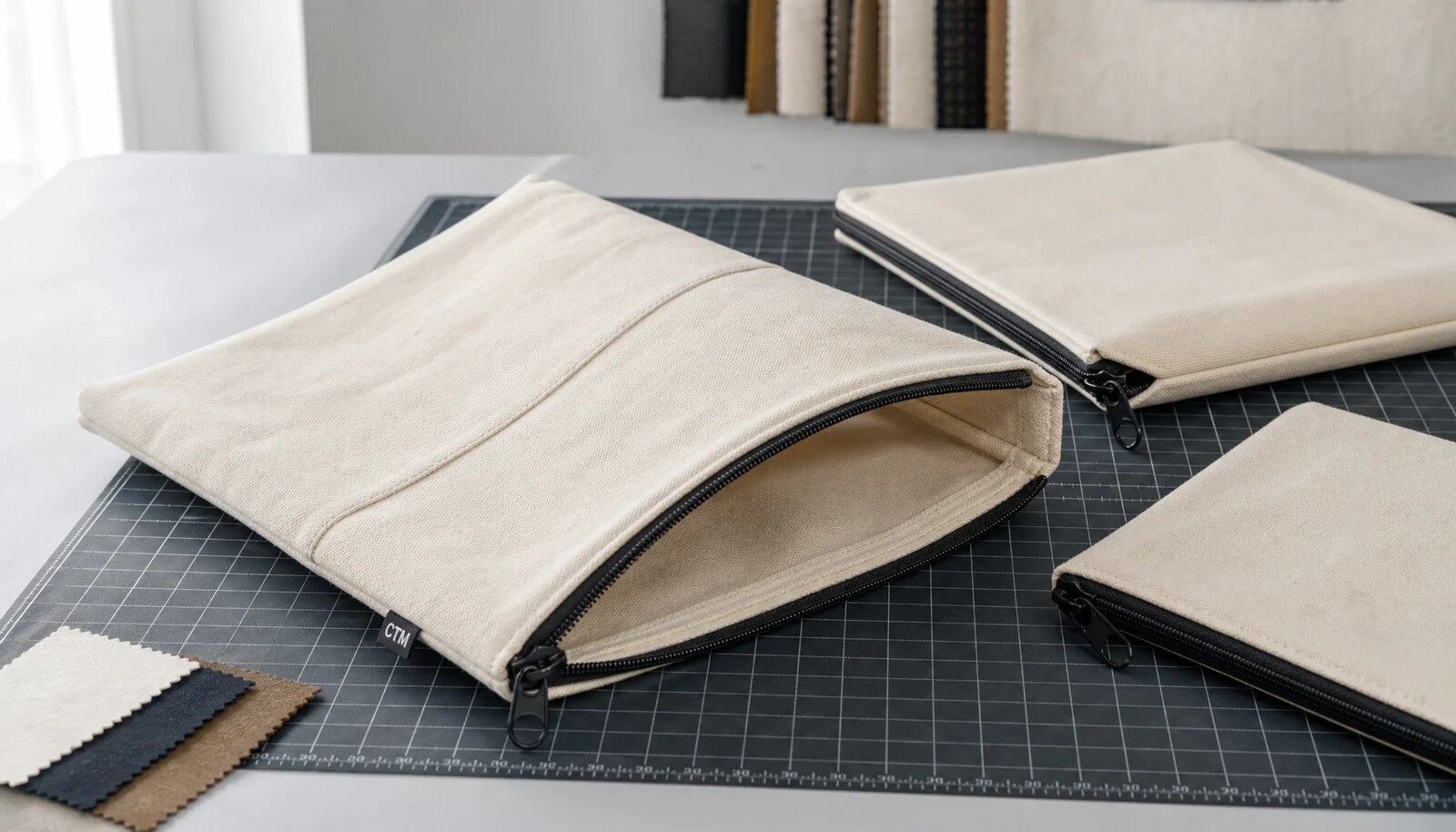 Natural canvas zipper portfolios with CTM side label on a clean studio worktable