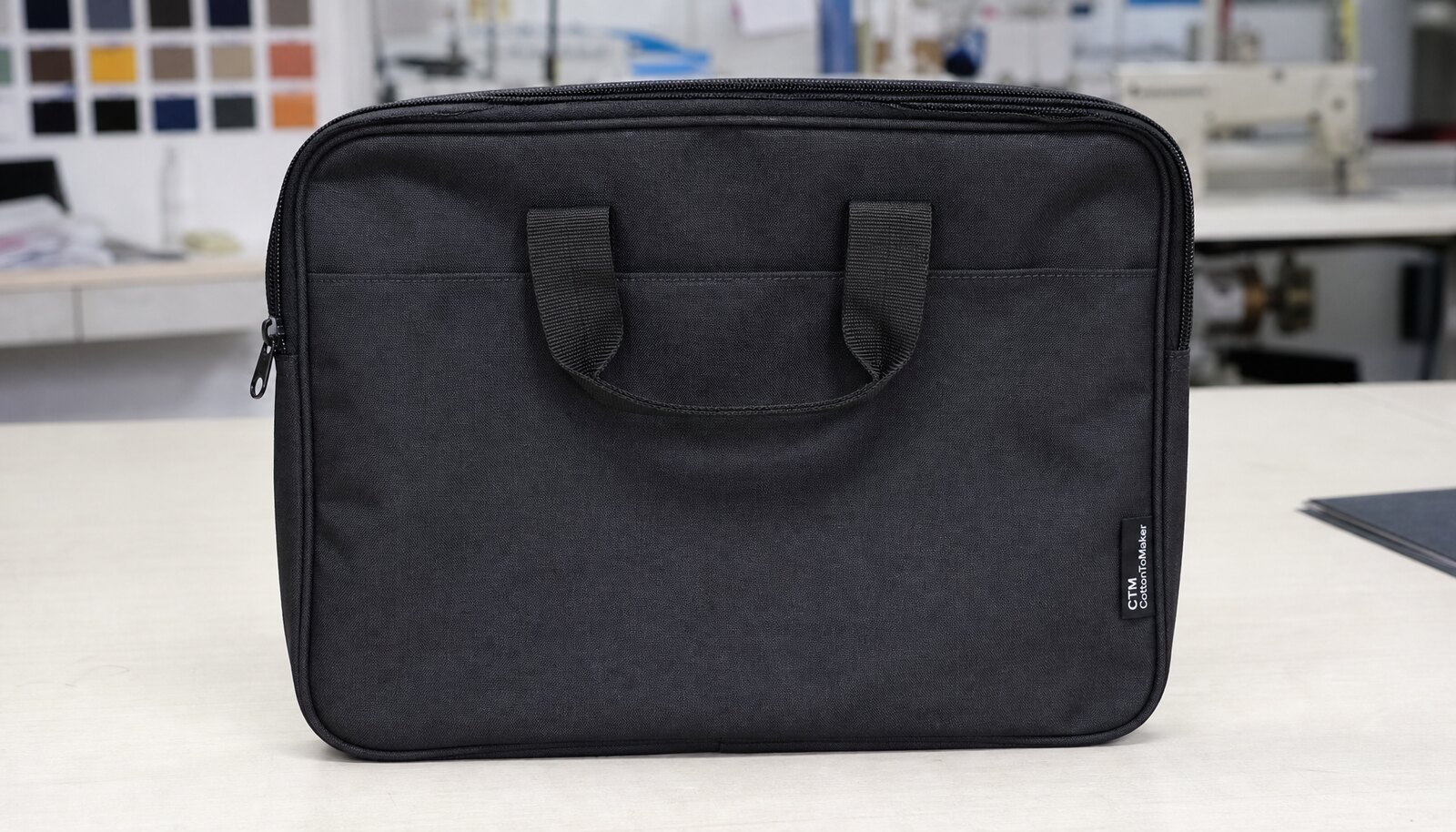 Photorealistic zipper conference bag with a CTM/CottonToMaker side label in a factory sample room.