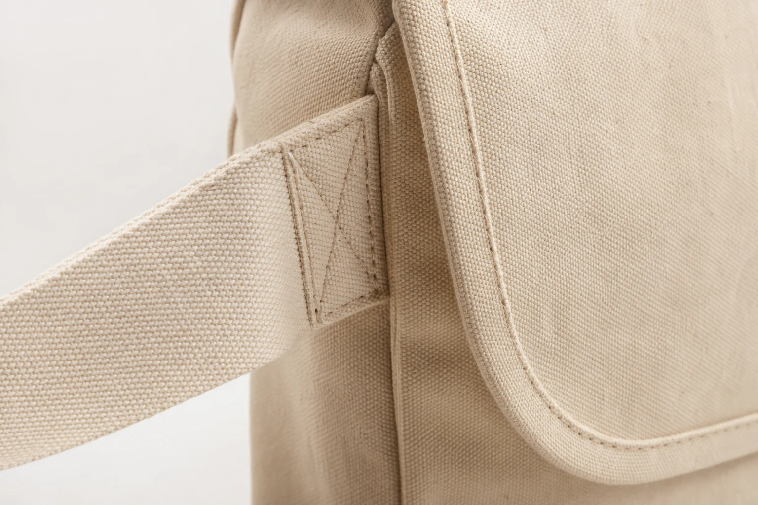 Messenger bag strap attachment, bartack stitching, and canvas weave detail