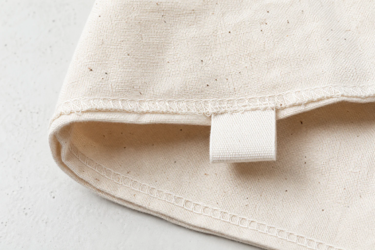 Organic cotton weave, seed flecks, folded hem, and seam detail